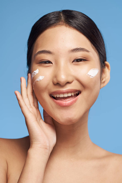 Nuori aasialainen nainen soveltamalla kosteusvoide hänen kasvonsa  - Valokuva, kuva