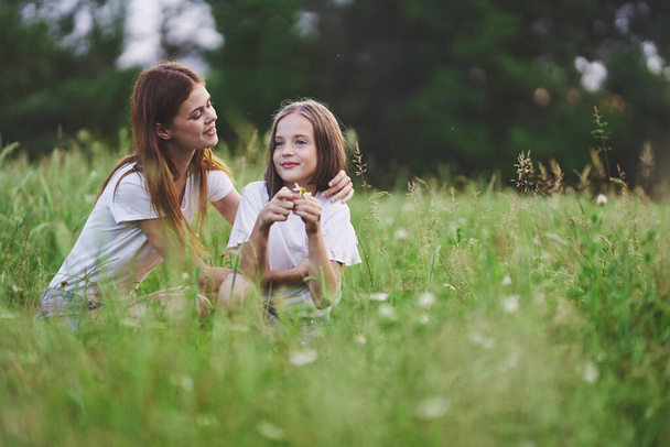 Young mother and her daughter having fun on camomile field - Photo, Image
