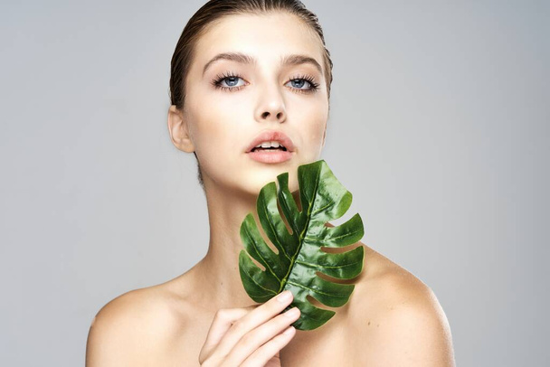 Young beautiful model posing with leaf in studio - Foto, Bild