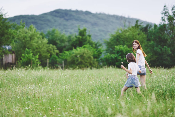 Jeune mère et sa fille s'amusent sur le champ de camomille - Photo, image