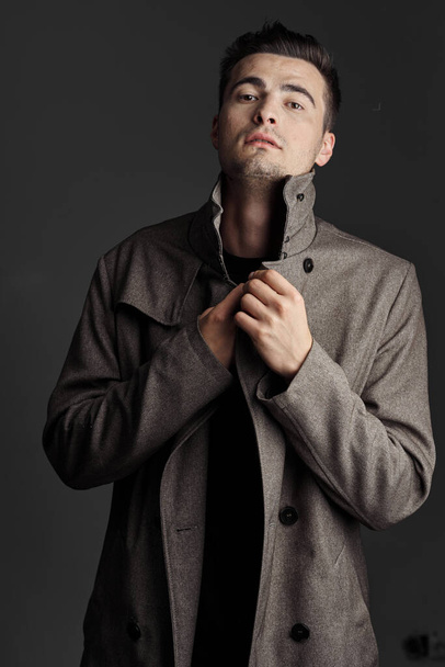 Portrait of young handsome man in coat   on dark background   - Zdjęcie, obraz