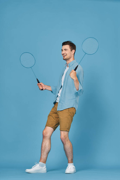 Young man  with rackets  isolated on blue background, studio shot    - Photo, Image