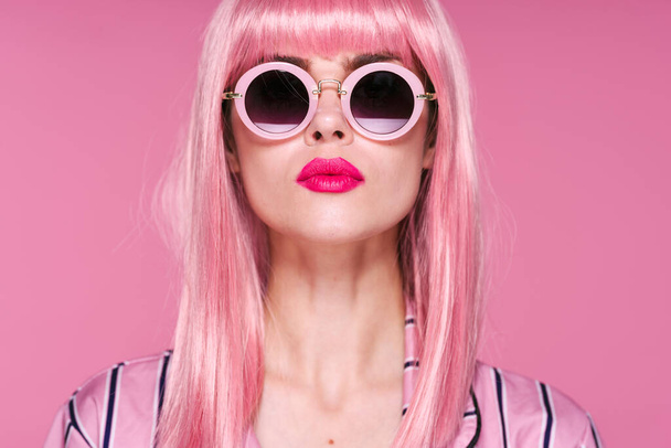 joven hermosa mujer en rosa peluca y gafas de sol posando en estudio
  - Foto, imagen