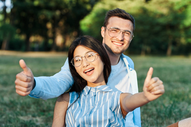 Jovem casal bonito no parque de verão dando polegares para cima  - Foto, Imagem