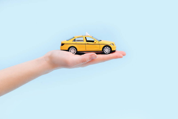 Stadttaxi und Lieferservice-Konzept. Spielzeug gelbes Modell eines Taxiwagens auf blauem Hintergrund. Kopierraum für Text, Banner. Online mobile Anwendung bestellen Taxi-Service. - Foto, Bild
