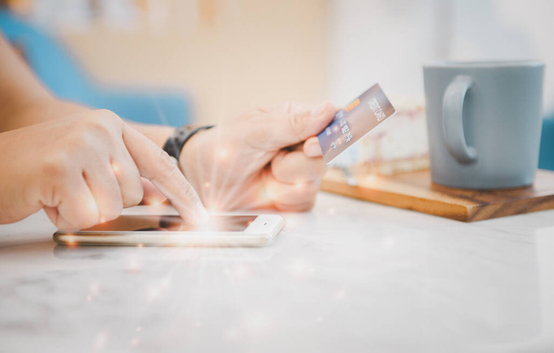 Parmakçı kadın cep telefonuna dokunuyor ve kahve kafesinde kredi kartı tutuyor. İnternetten alışveriş yapıyor. - Fotoğraf, Görsel