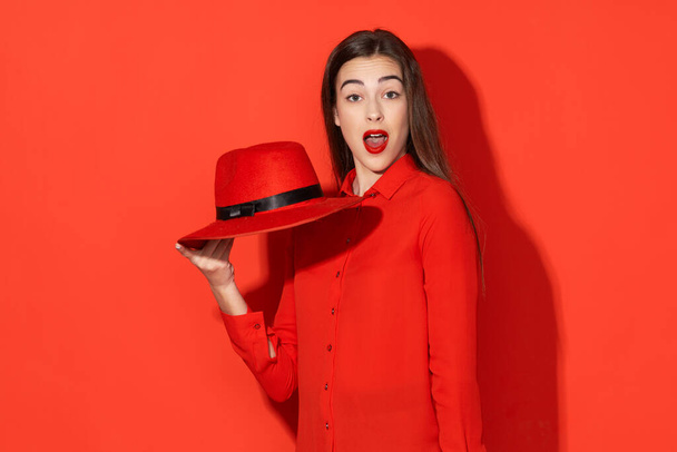 Studio shot. Young beautiful  surprised woman in red  isolated on red background - Foto, Imagen