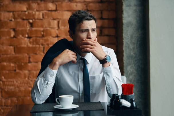 Joven hombre de negocios guapo cansado sentado en la cafetería  - Foto, imagen