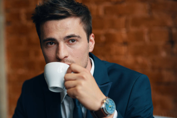 オフィスにコーヒーカップを持つ若いビジネスマン  - 写真・画像