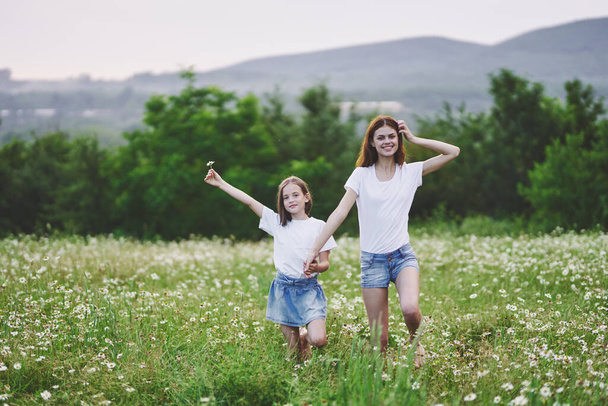 Jovem mãe e sua filha se divertindo no campo de camomila - Foto, Imagem