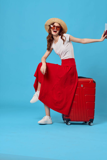 Νεαρή γυναίκα με κόκκινη βαλίτσα στο στούντιο - Φωτογραφία, εικόνα