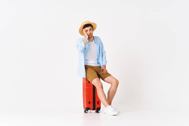 Young man with red suitcase in studio - Photo, Image