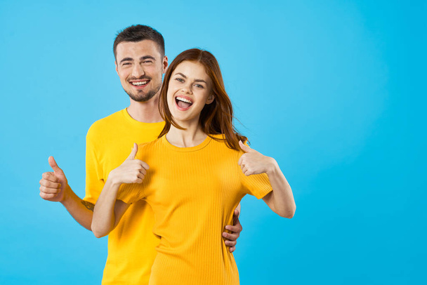 young man and woman in studio  showing thumbs up on blue background  - Photo, Image