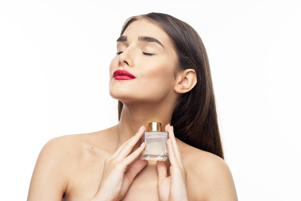 Młoda piękna kobieta trzyma butelkę perfum w studio - Zdjęcie, obraz