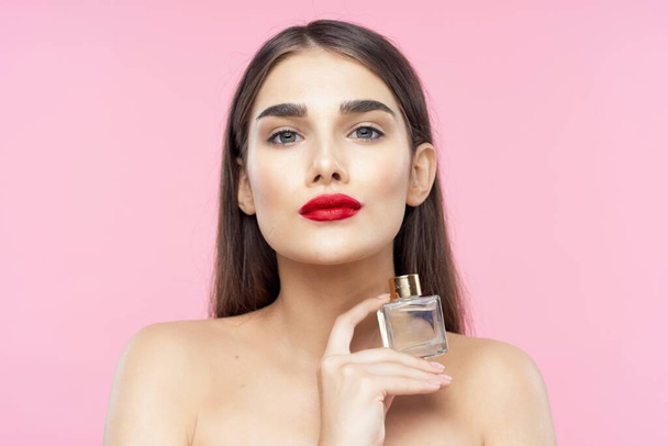 Egy fiatal, gyönyörű nő arcképe parfümös üveggel. Stúdió felvétel - Fotó, kép