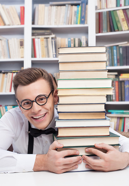 Young man in library and hugging a book stack - Foto, Bild