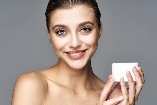 Студийный снимок молодой красивой женщины со сливками, косметический продукт на изолированном фоне
 - Фото, изображение