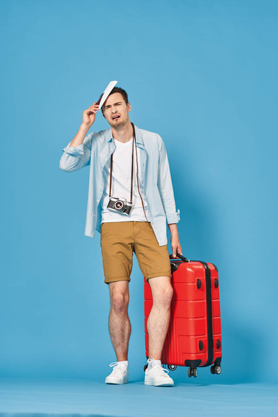 Young man with red suitcase in studio - Фото, изображение