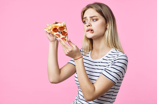 İzole edilmiş arka planda pizza yiyen güzel, üzgün bir kadın.  - Fotoğraf, Görsel