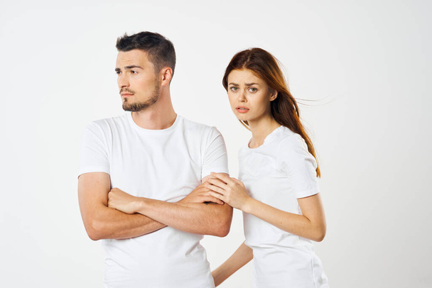 young beautiful couple in  t-shirts posing in studio on isolated background - Фото, изображение