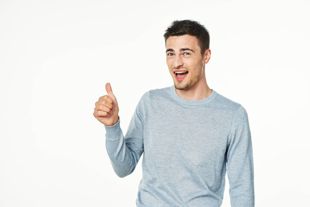 Jonge knappe man met duim omhoog in de studio, geïsoleerde achtergrond - Foto, afbeelding