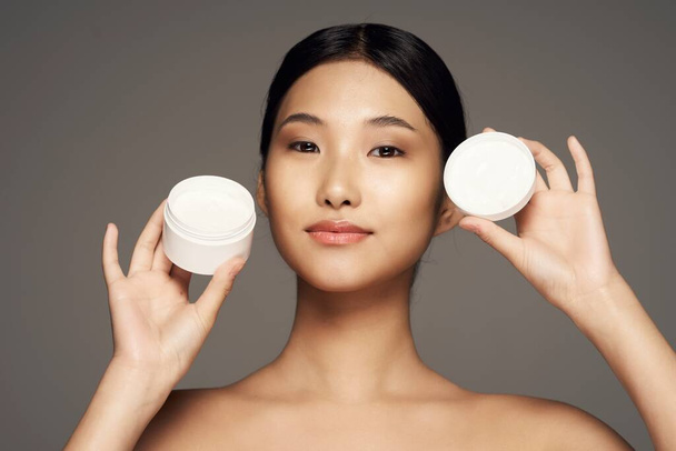 Young beautiful asian woman  holding cream   isolated  - Fotografie, Obrázek