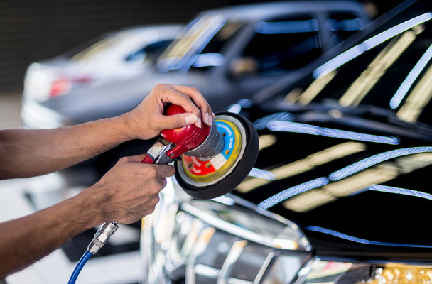 The worker polishes a car with the electric tool. - Foto, afbeelding
