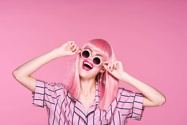 jeune belle femme en perruque rose et lunettes de soleil posant en studio  - Photo, image