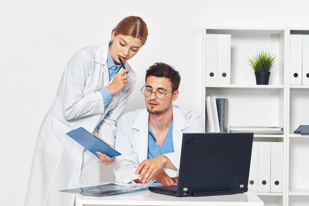 Jonge arts en verpleegkundige met laptopm in ziekenhuiskantoor  - Foto, afbeelding