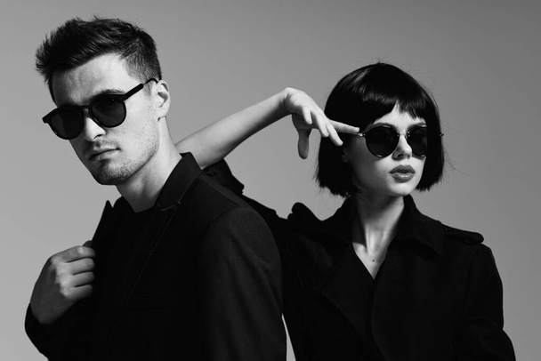Young beautiful couple in sunglasses posing in studio. Black and white.    - Photo, Image