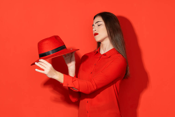 Colpo in studio. Giovane bella donna in cappello rosso tenuta isolata su sfondo rosso - Foto, immagini