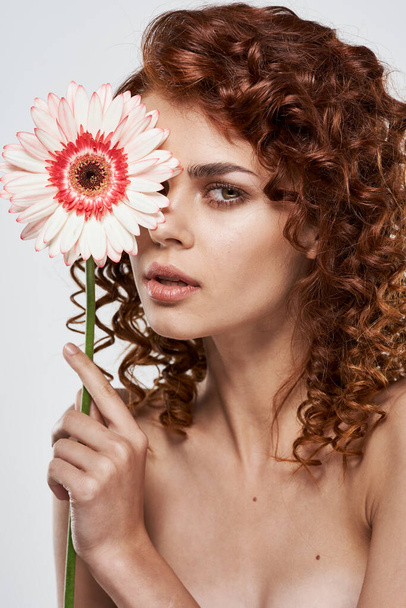 Young woman with flower posing in studio - Фото, зображення