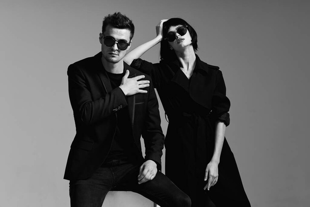 Young beautiful couple in sunglasses posing in studio. Black and white.    - Photo, Image