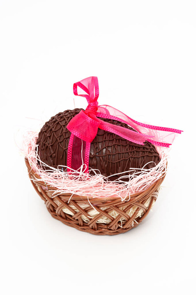 ギフトのための赤いリボンと美しいウィッカーバスケットのチョコレートの卵。母の日、バレンタインデー、イースターのお祝い。白い背景に隔離されている。縦射. - 写真・画像