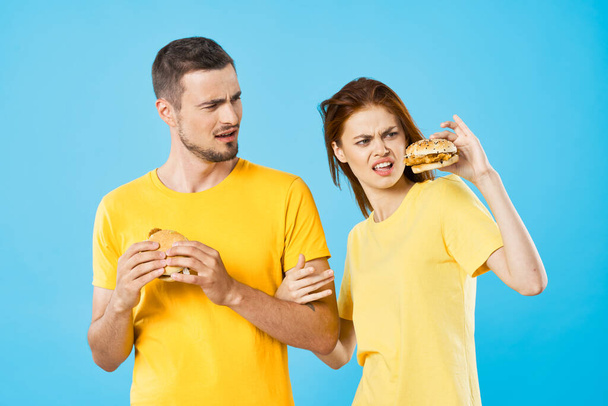 Joven hermosa pareja comiendo hamburguesas. Captura de estudio - Foto, imagen