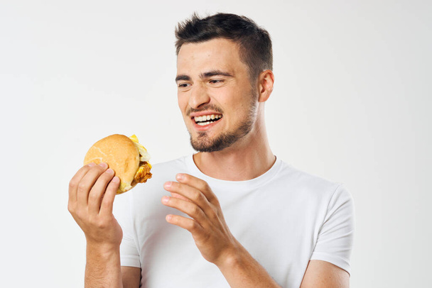 Młody człowiek z hamburgerem w studio  - Zdjęcie, obraz
