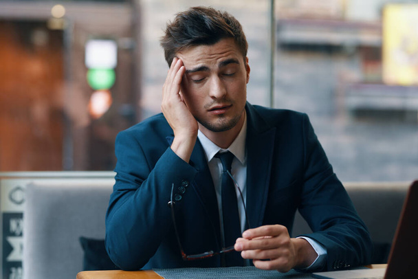 Joven hombre de negocios guapo sentado en la cafetería con dolor de cabeza  - Foto, Imagen