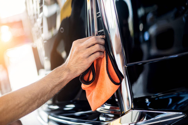 Car service worker polishing car with microfiber cloth. - Zdjęcie, obraz