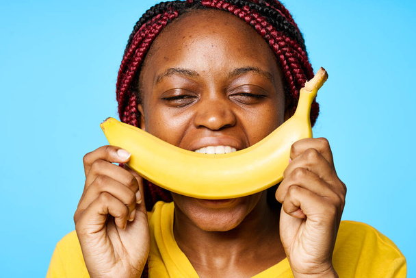 Young  woman  with banana   isolated on blue background - Foto, Bild