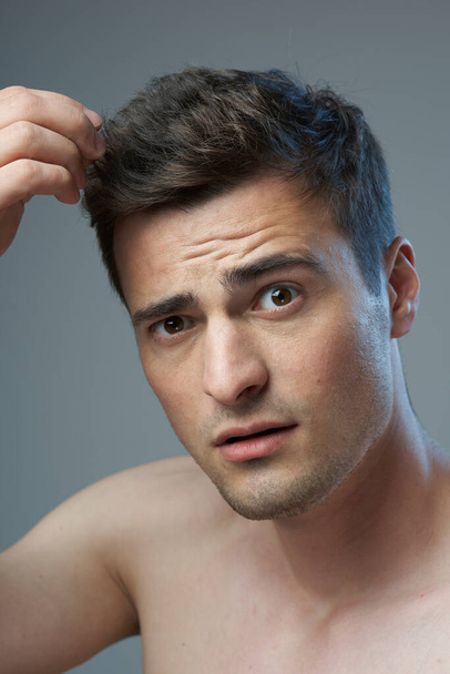 Zdjęcia studyjne. młody przystojny mężczyzna z nowoczesny fryzura pozowanie w studio, odizolowany  - Zdjęcie, obraz