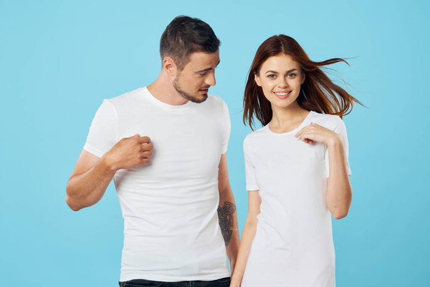 молодая красивая пара в футболках позирует в студии на изолированном фоне   - Фото, изображение