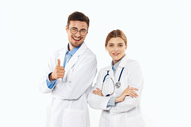 Νεαρός γιατρός με τον αντίχειρα επάνω και νοσοκόμα στο στούντιο, απομονωμένο υπόβαθρο.  - Φωτογραφία, εικόνα