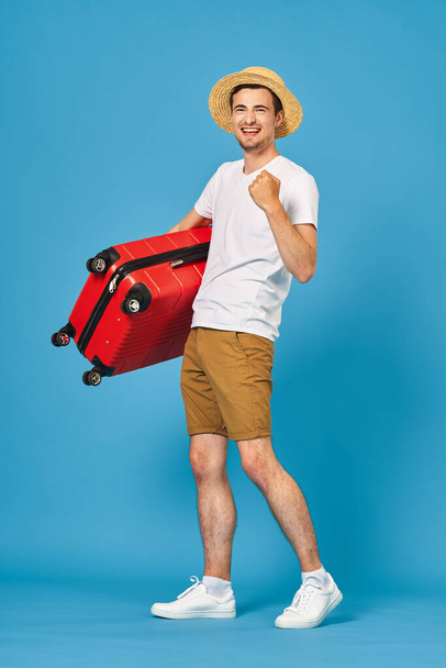 Młody mężczyzna z czerwoną walizką w studio - Zdjęcie, obraz
