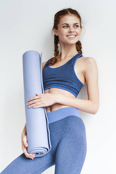 Jonge mooie vrouw met yoga mat - Foto, afbeelding