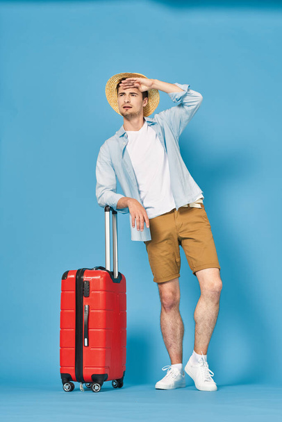 Young man with red suitcase in studio - Fotoğraf, Görsel