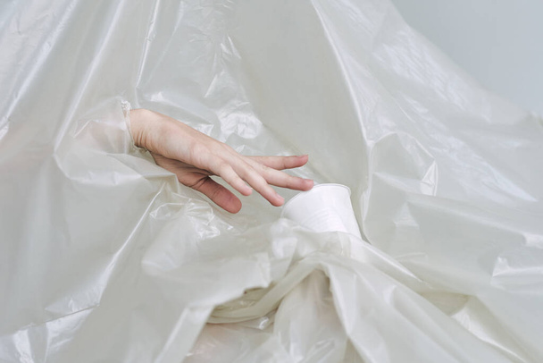 Plastik ve polietilen yırtıklar olan bir kadın eli. - Fotoğraf, Görsel