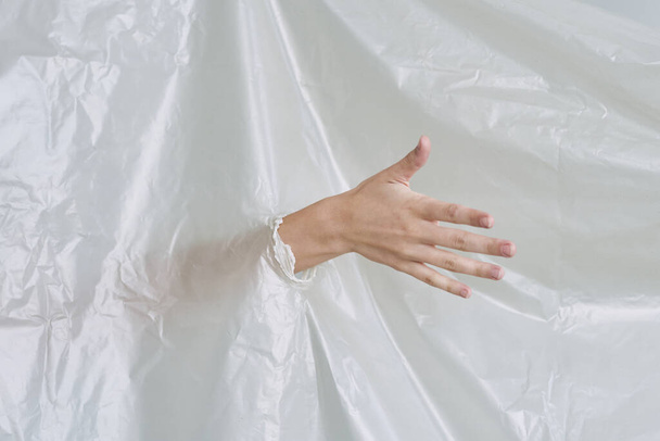 Kadın eli plastiği yırtıyor, polietilen. - Fotoğraf, Görsel