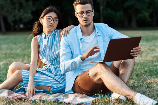junge Studenten mit Laptop auf dem Rasen  - Foto, Bild