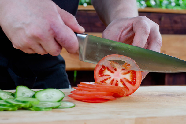 tomatoes in the section. the cook slices a tomato into circles - 写真・画像
