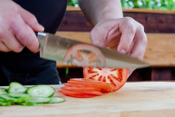 tomatoes in the section. the cook slices a tomato into circles - Foto, Bild